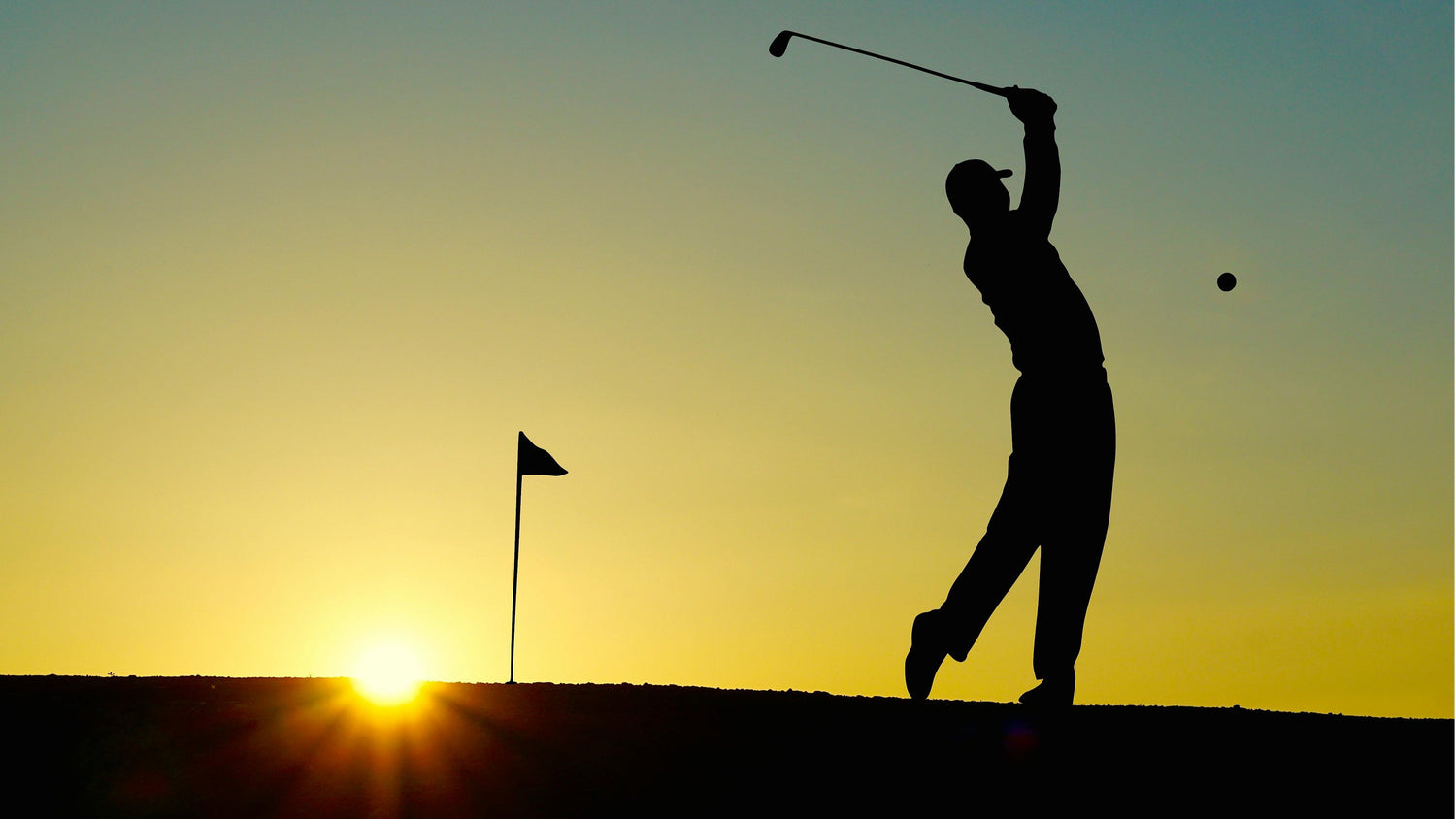 Golfare i svart för grafisk effekt svingar sin golfklubba i solnedgången