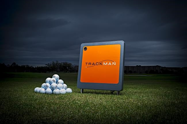 Trackman skärm stående med en hög av golfbollar vid sidan