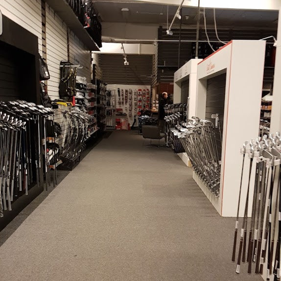 Upphängda golfklubbor längs väggen i en butik